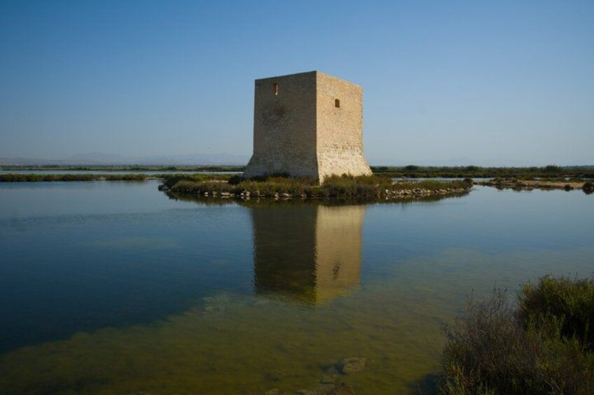 A solitary tower on a small island surrounded by calm water. 5