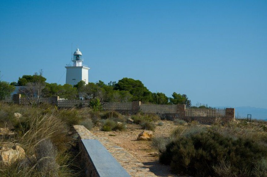 A lighthouse on a hill, surrounded by a stone wall and vegetation. 3