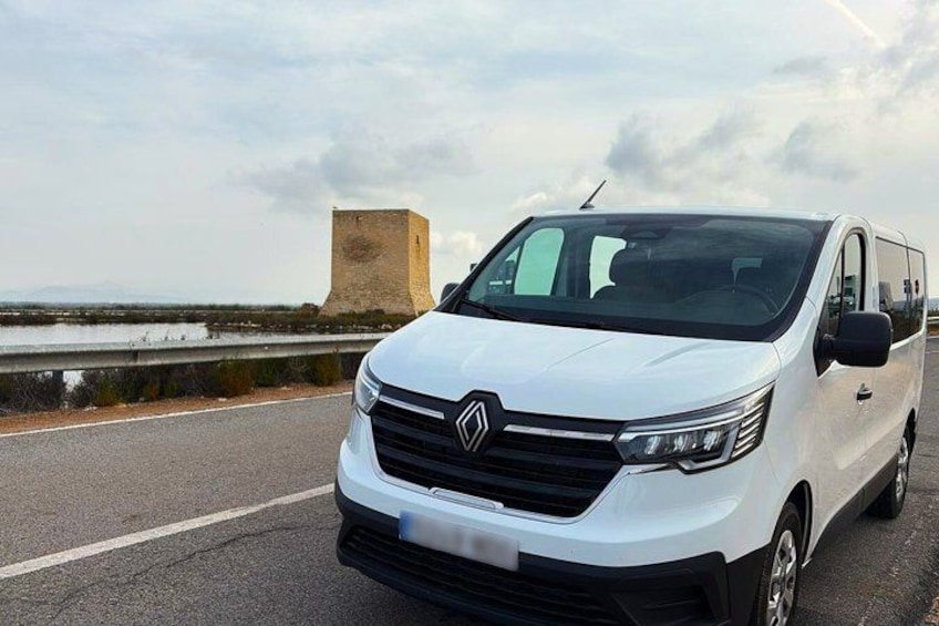 A white van parked on a road with a body of water and a tower in the background. 1