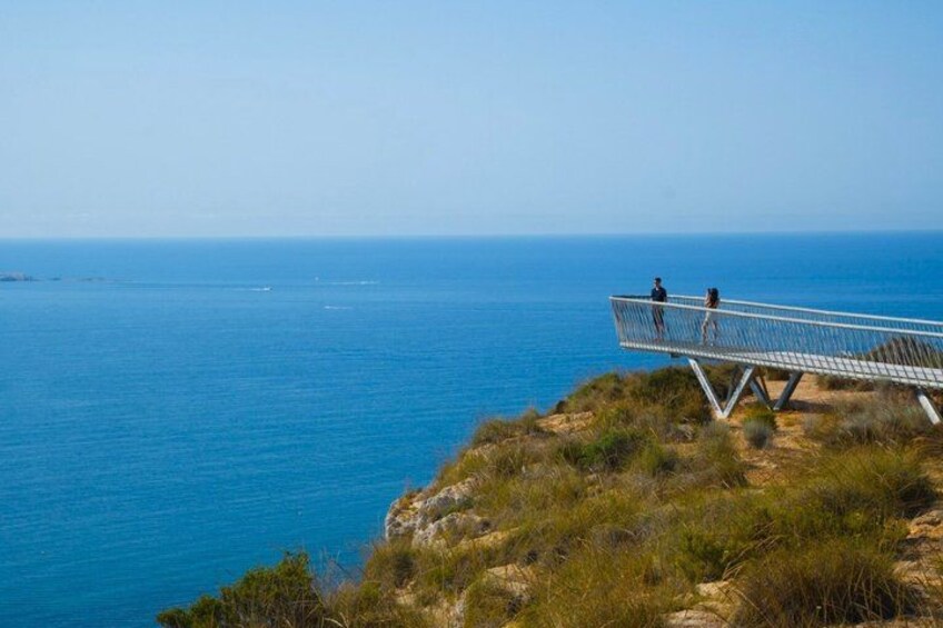 A coastal landscape with a metal walkway overlooking the sea. 4