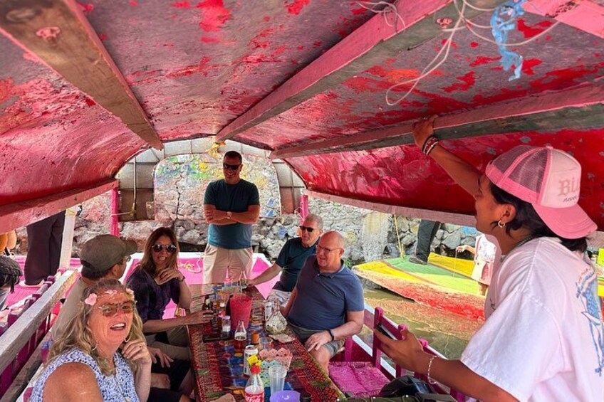 A group of people sitting at a table under a tent with a red interior. 3