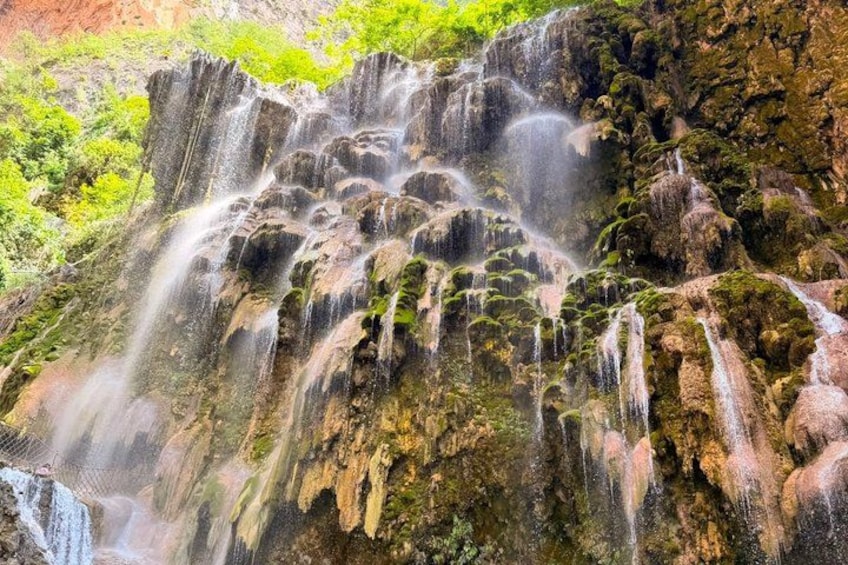 A multi-tiered waterfall with cascading water surrounded by lush greenery. 5