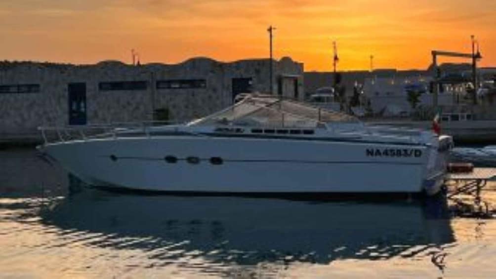 A boat docked at a marina with a sunset in the background. 1
