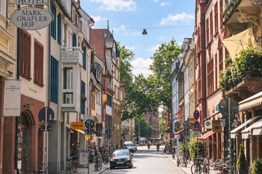 A street lined with historic buildings, a bicycle, and a car. 3