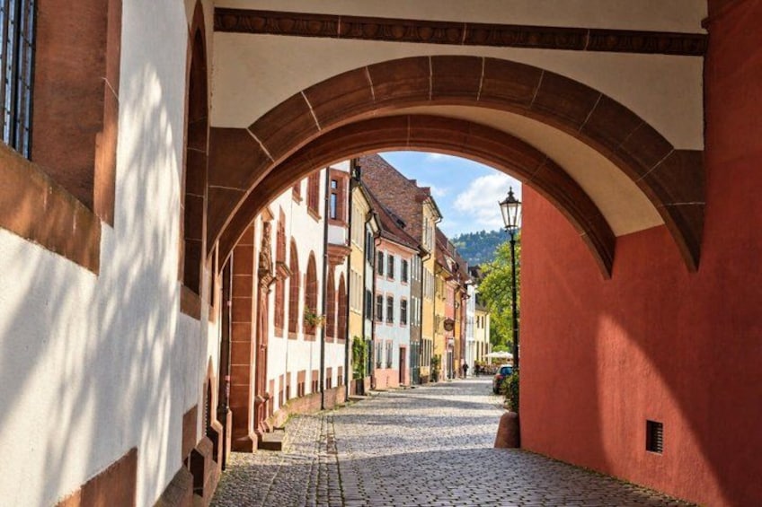 A cobblestone street under an arched bridge with buildings on either side. 5