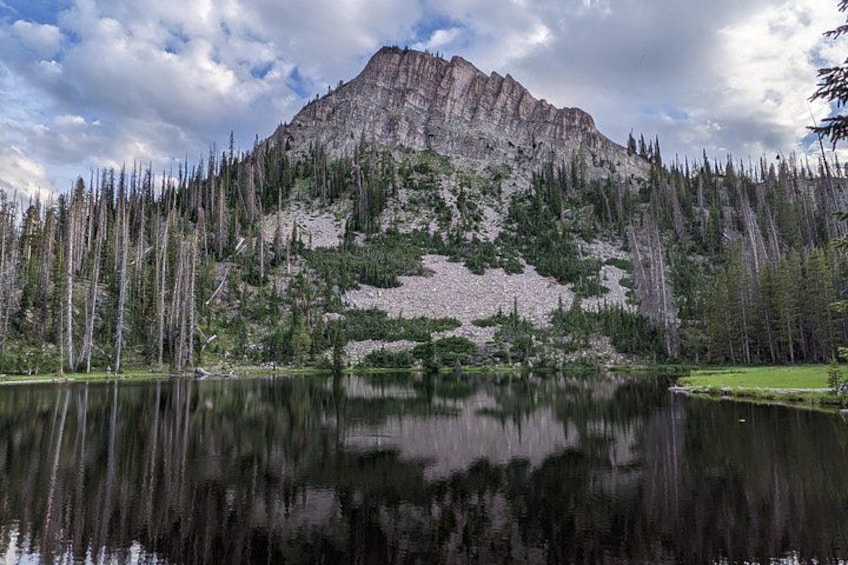 A mountain with a lake in the foreground and a forested area. 1