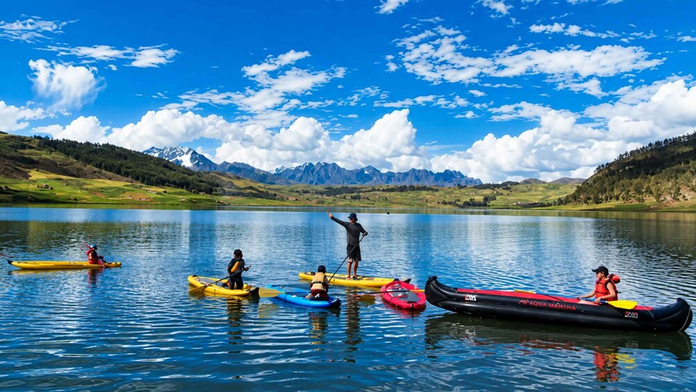 A group of people kayaking on a calm lake with mountains in the background. 3