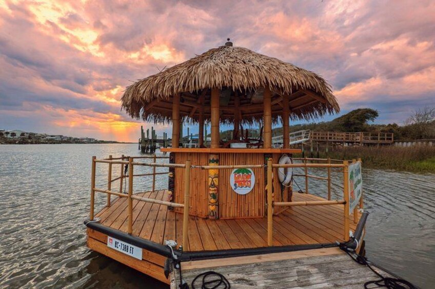 A wooden boat with a thatched roof, a sign with a tropical fruit logo, and a dock in the background. 4