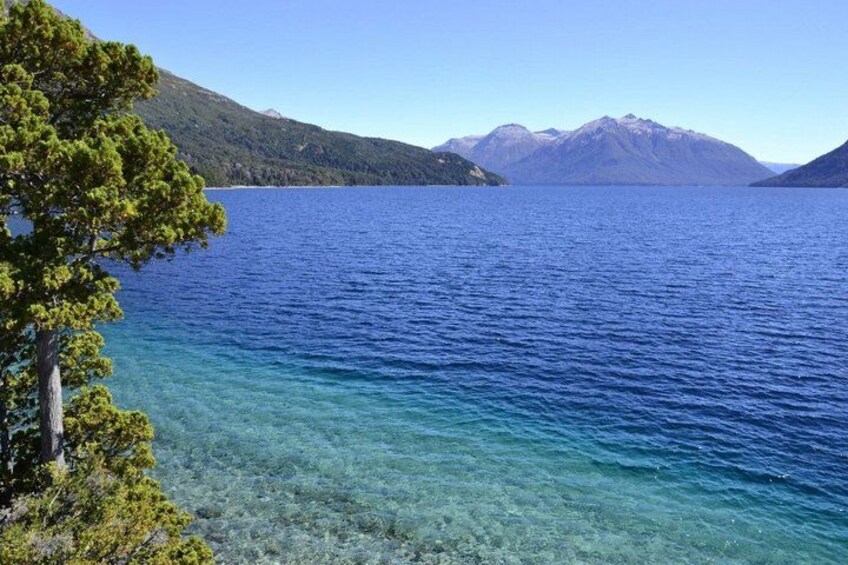 A clear blue lake surrounded by mountains and trees. 3