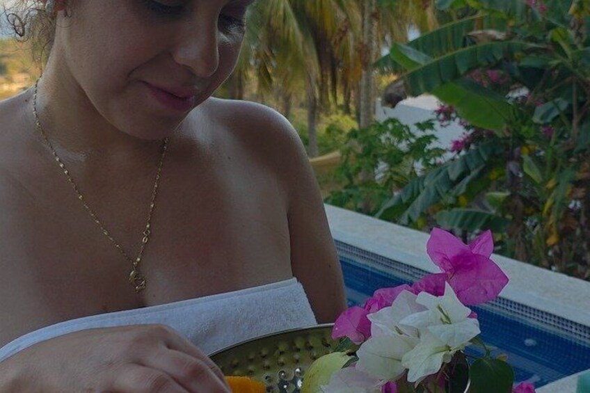 A person reading a book by a pool with flowers and greenery in the background. 5