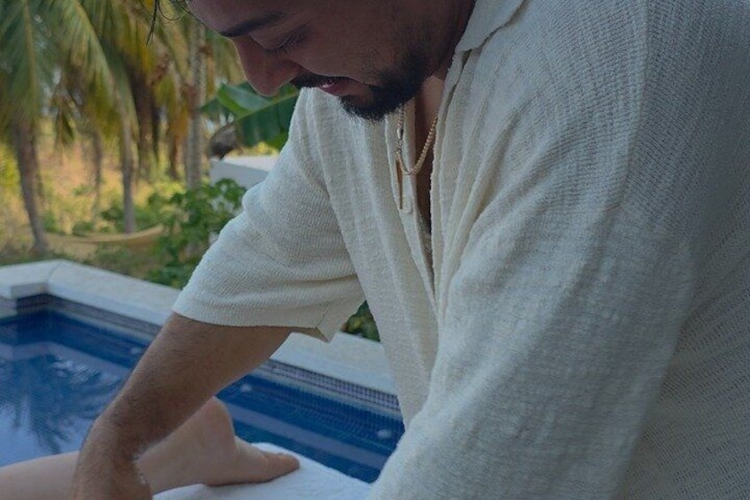 A person leaning over a pool with a white shirt and a necklace. 1