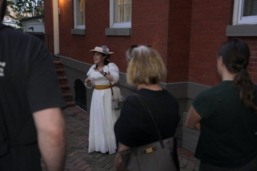 A person in traditional attire standing on a brick pathway, with a building in the background. 2