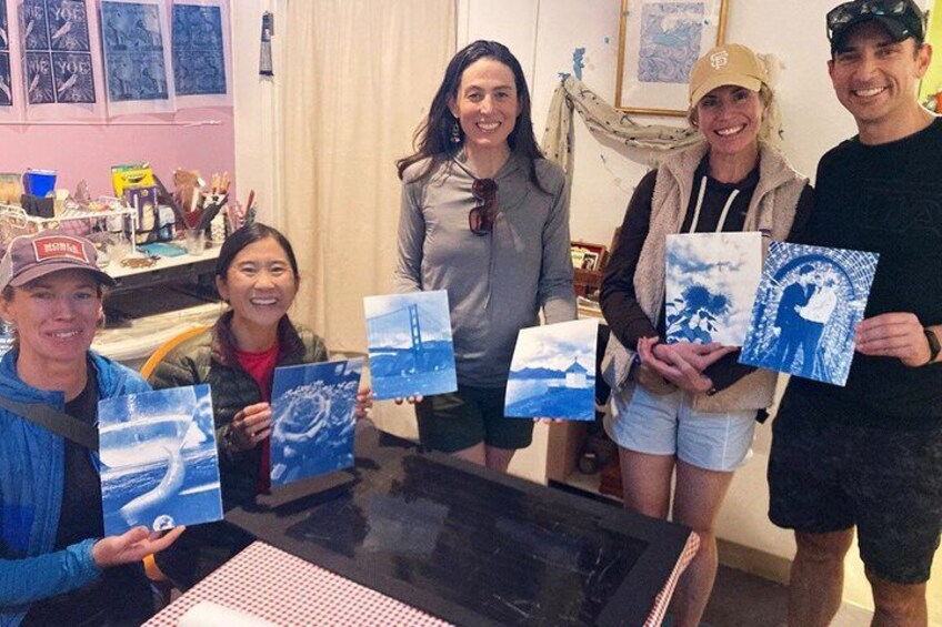 A group of people holding framed artwork at a table. 2