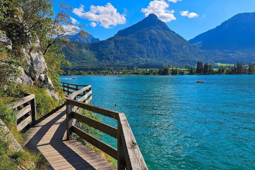 A wooden pier leading to a turquoise lake with mountains in the background. 1