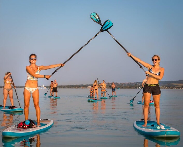 People paddleboarding on a calm body of water with a clear sky. 1