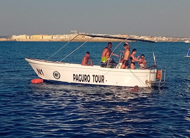 A boat named PAGURO TOUR with people on board, floating on water with a cityscape in the background. 2