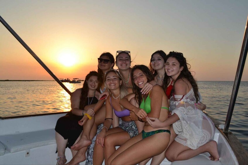 A group of people on a boat at sunset with the sun low on the horizon. 1