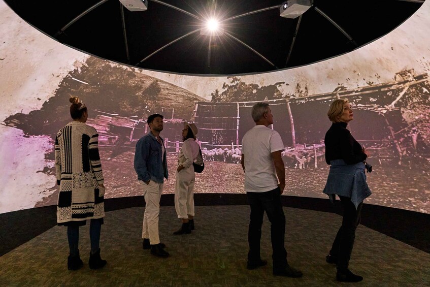A group of people observing a large projection of a historical scene. 5