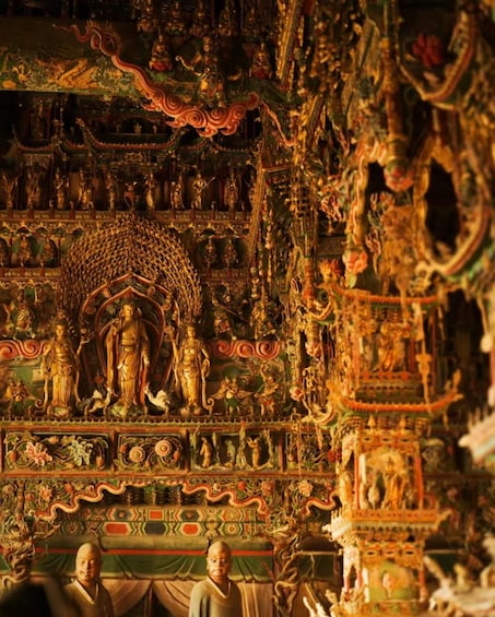 A detailed temple interior with ornate carvings, statues, and a central figure surrounded by smaller figures. 1