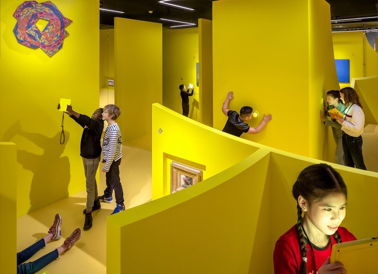 Ein hell erleuchteter, gelber Innenraum mit geometrischen Formen und einem farbenfrohen, abstrakten Kunstwerk an der Wand. 5