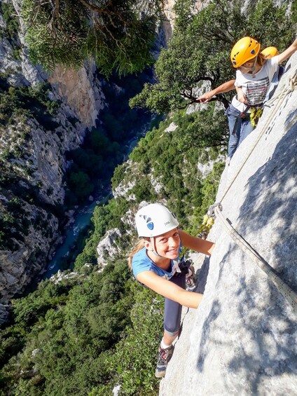 A person rappelling down a cliff with a river and forest in the background. 2
