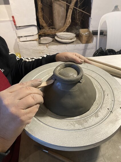 A person shaping a clay pot on a pottery wheel. 5