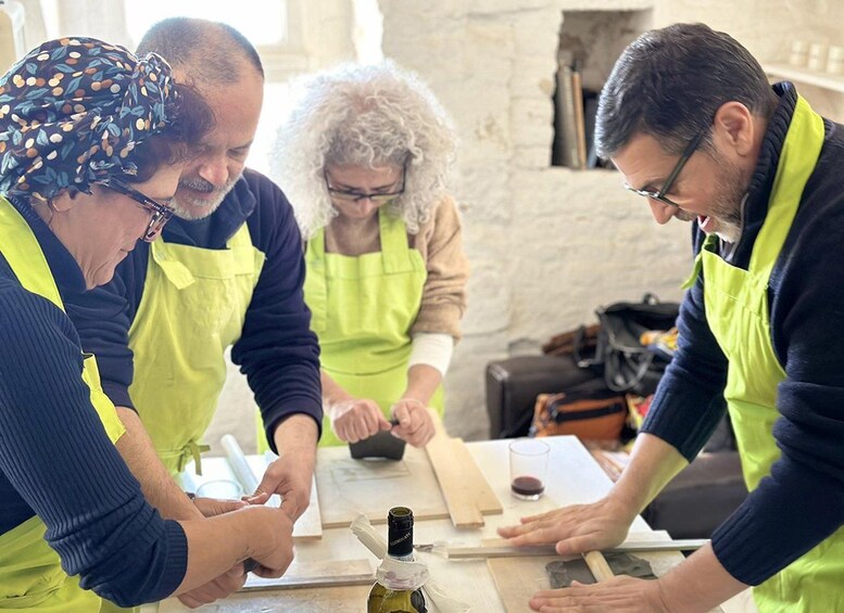 Three people wearing aprons working with wood and tools on a table. 4