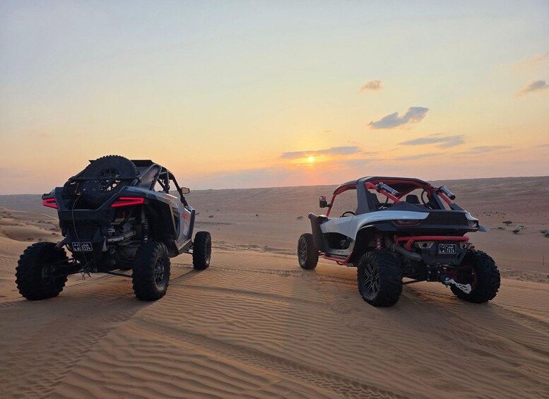 Two off-road vehicles parked on a desert sand dune at sunset. 3