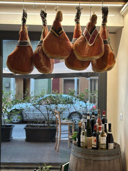 Hanging cured meats and a barrel of wine bottles. 4