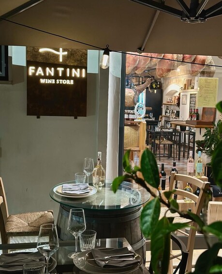 A wine store interior with a round table set for dining, a wine bottle, and a sign that reads 'FANTINI WINE STORE.' 1