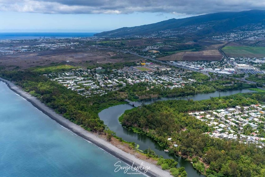 An aerial view of a coastal town with a river, residential areas, and a mountainous backdrop. 2