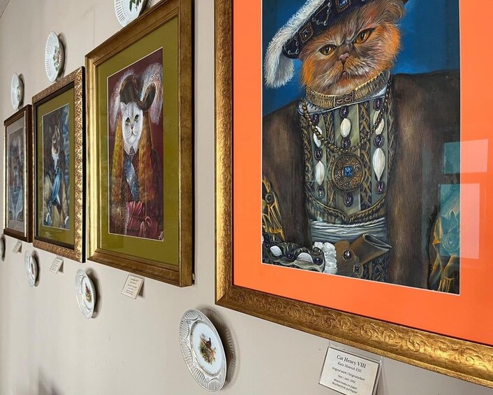 Un mur orné de tableaux encadrés, dont une peinture représentant un chat portant des vêtements élaborés. 2