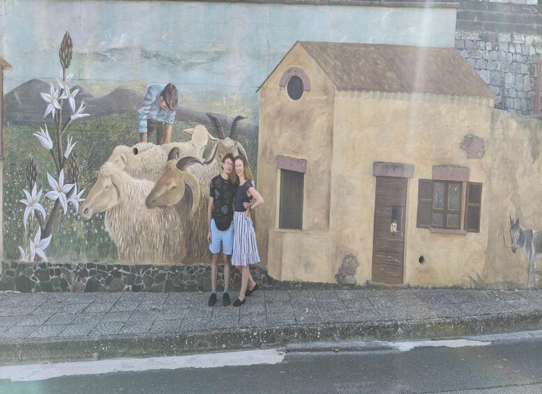 A mural with a cow, a small house, and a person standing in front of it. 5