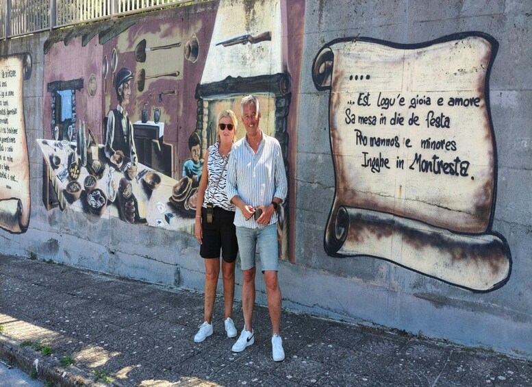 A mural on a wall with a man and a woman standing in front of it. 3