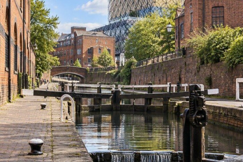A canal with a bridge, brick buildings, and a water pump. 4