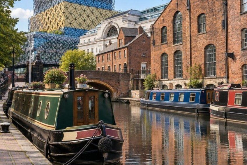 A narrow canal with boats, brick buildings, and a modern glass structure in the background. 5