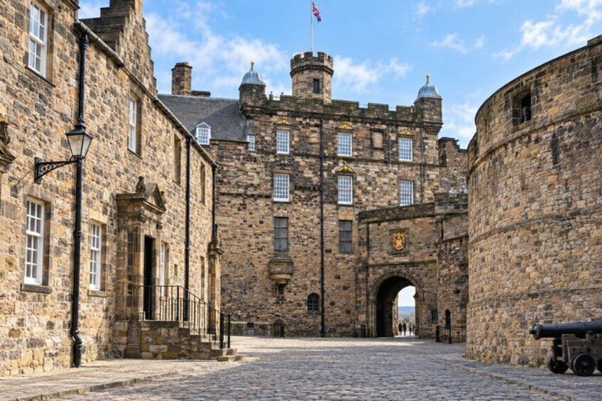 A historic stone building with a central archway, a flag, and a cannon. 2