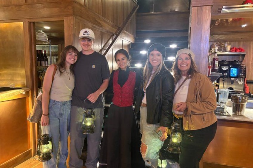 A group of people in a bar setting with wooden interiors and bottles on shelves. 4