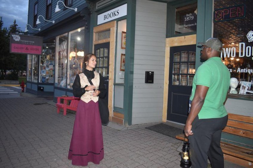 A street with a bookstore, a red bench, and a person holding a bottle. 5
