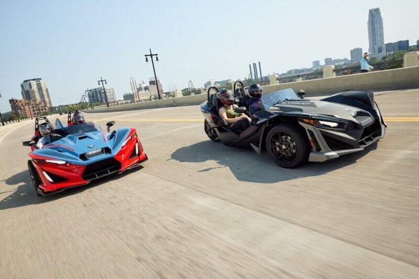 Two sports cars on a highway with a city skyline in the background. 2