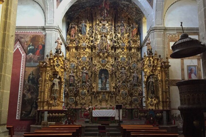 An ornate church interior with a large altar, religious statues, and detailed wall paintings. 4