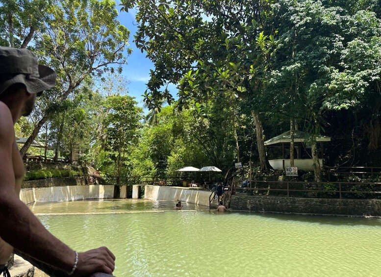 A person in a natural setting with a pool, trees, and a no smoking sign. 2