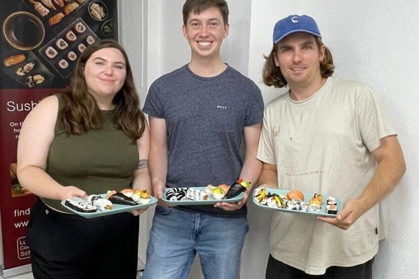 Three people holding plates of sushi. 3