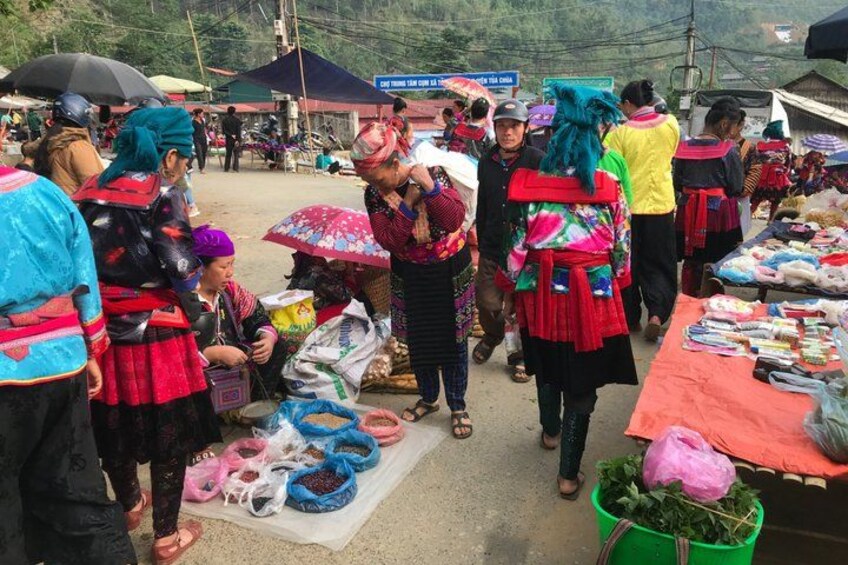 A market scene with people in traditional attire, colorful fabrics, and various goods displayed on tables. 5