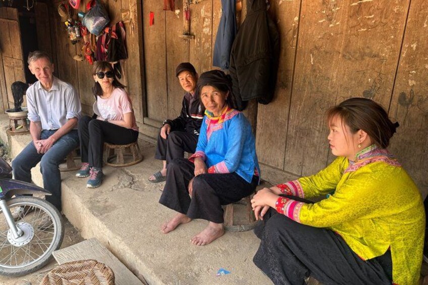 A group of people sitting on steps outside a wooden building. 3