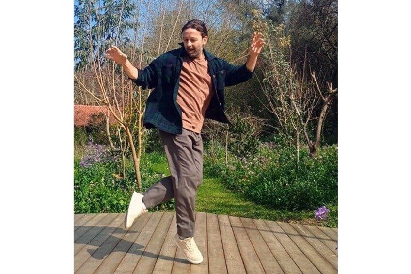 A person jumping in a garden with trees and a wooden deck. 3