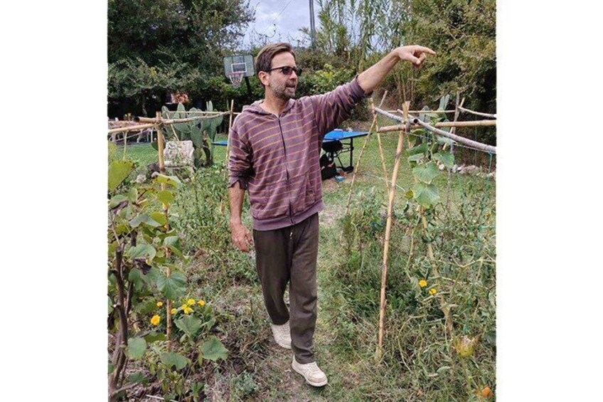 A person standing in a garden with a trellis structure. 2