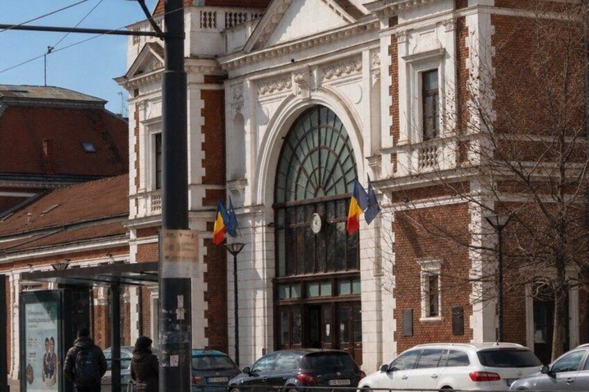 A historic building with a large arched window and flags. 2