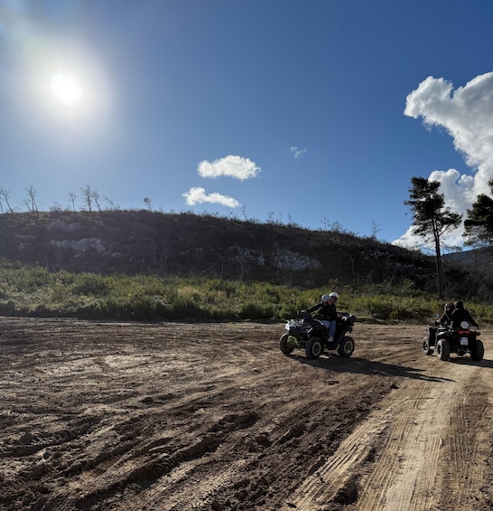 Two off-road vehicles on a dirt path with a clear sky and sparse vegetation. 4