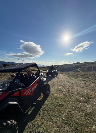 Two off-road vehicles on a dirt path with a clear sky and distant mountains. 5